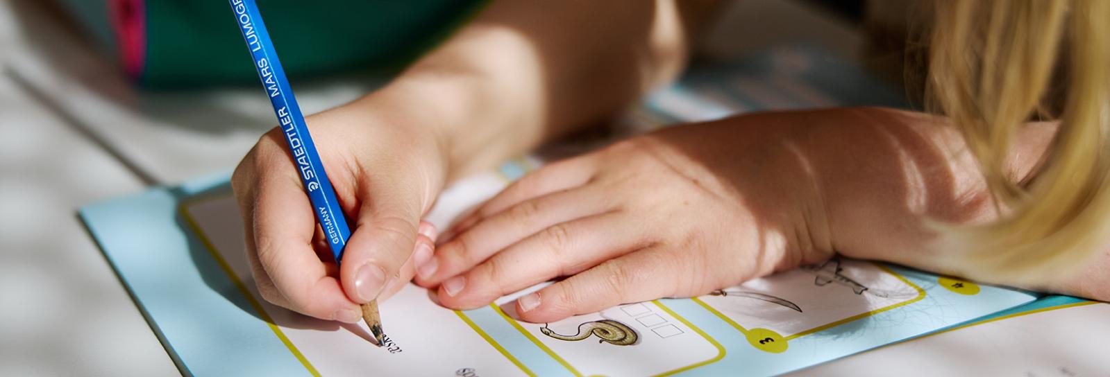 Student writing in a task book in class